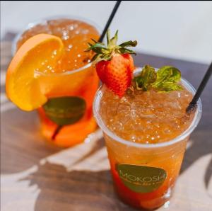 帕拉利米尼Mythical Sands Resort - Antonios的木桌旁的2杯鸡尾酒,包括草莓和橙子