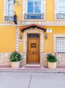 卡尼亚马雷斯Hostal Cañamares的黄色的建筑,有木门和两株植物