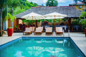 贝岛Fleurs d'Ylang的房屋旁的游泳池配有椅子和遮阳伞