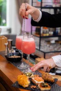 罗马Mangili Garden Hotel的把粉红色的饮料倒进玻璃杯的人