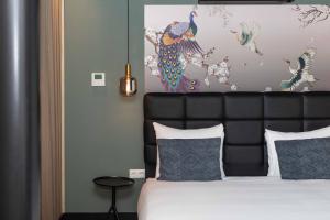 阿姆斯特丹逸居酒店的一间卧室配有一张带黑色床头板和绘画的床。