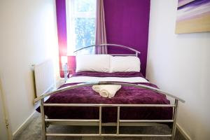 曼彻斯特Purple Blossom, cosy 2 bed apartment, near Didsbury, free parking的紫色墙壁间的一张床位