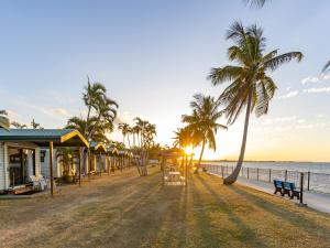 鲍恩NRMA Bowen Beachfront Holiday Park的棕榈树和房屋的海滩和海洋