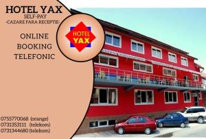 肯佩尼Hotel Yax的一座红色的建筑,前面有汽车停放
