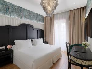 塞维利亚H10柯里基多精品酒店 的一间卧室配有一张大床、一张桌子和一个吊灯。