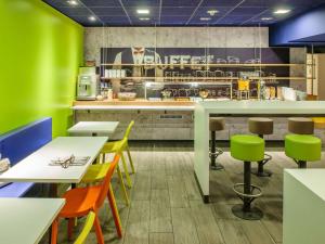 维利希ibis budget Duesseldorf Willich的餐厅拥有绿色的墙壁和桌椅