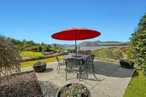 格伦科Skyfall Glencoe at Creag an-t Sionnaich的庭院里配有桌椅和红伞