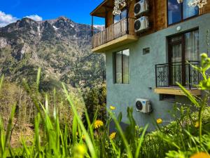 KhuloHotel Khulo lnn的带阳台的度假屋,享有山脉背景