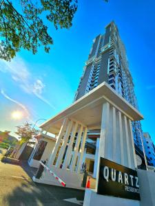 马六甲Quartz Paragon Suites Melaka By GGM的公寓大楼前面有标志