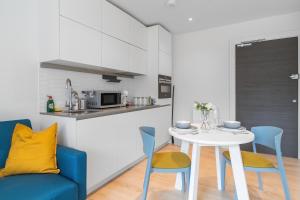 伦敦Livestay-Modern Apartments Next To Wembley Stadium的厨房以及带白色桌椅的用餐室。