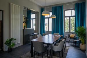 布鲁日Havenhuis Brugge的一间设有蓝色窗帘和桌椅的用餐室