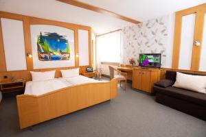 Waldkappel斯特恩兰德酒店的一间卧室配有一张床、一张沙发和一台电视。