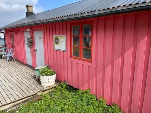 巴尔斯塔Kræmmervika Rorbuer - Rustic Cabins in Lofoten的红色的建筑,设有甲板和桌子