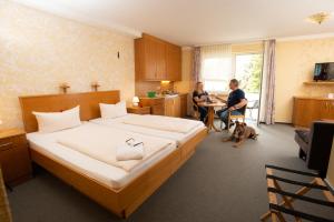 Waldkappel斯特恩兰德酒店的一间卧室,卧室里设有床,还有女人和狗