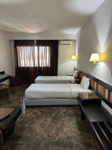 拉巴特Ourida Urban Hotel Rabat的酒店客房配有两张床和一张书桌