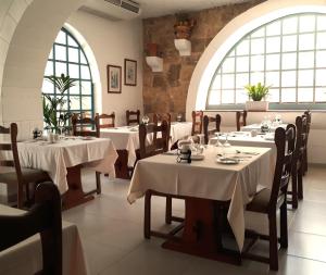 沙拉聚宝盆酒店的餐厅设有白色的桌椅和窗户。