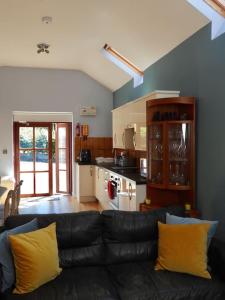 特兹西尼德Nature's Oasis: Pet-Friendly Snowdonia Cottage的一间带黑色沙发的客厅和一间厨房