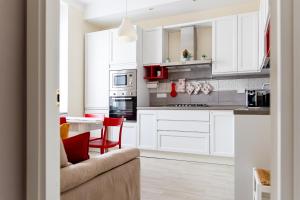 斯培西亚Myro's House的白色的厨房配有红色的椅子和桌子