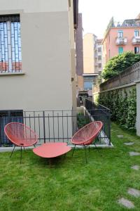 米兰La Maison City Life Apartments的两个红色桌子坐在院子里的草地上