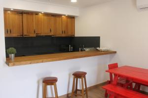 Casa do Centro的厨房配有木制橱柜、红色桌子和凳子