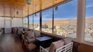 瓦迪穆萨Beit Alshabaan Inn的配有桌椅和大窗户的客房