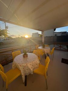 巴雷里尼亚斯Pousada Mangaba的一个带桌子和黄色椅子的庭院,享有日落美景