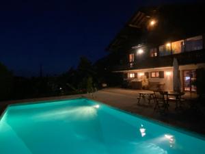 Collonges-sous-SalèveCabane Jacomeli Genève的夜晚的蓝色游泳池与房子