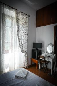 Sálakos尼姆费旅馆的一间卧室配有一张床、一张书桌和一个窗户。