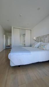 孔波尔塔Recantus Comporta的卧室铺有木地板,配有一张大型白色床。