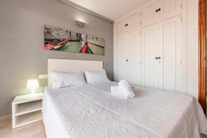拉皮内达Aimar Atico duplex Playa la Pineda Port Aventura的卧室配有一张白色床,墙上挂有绘画作品