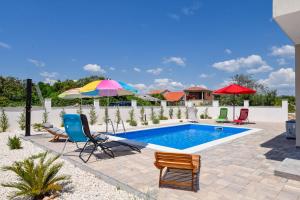 亚德里亚Villa Adriatic Sunset的庭院内一个带椅子和遮阳伞的游泳池