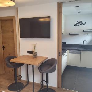 加尔蒂Apart Bergli的厨房配有一张桌子和两把椅子,墙上配有电视。