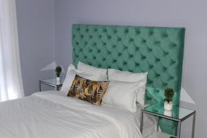 卢萨卡Blue Agave MH的一间卧室配有一张大床和绿色软垫床头板