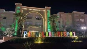 莫纳斯提尔Palm lake resort Folla Monastir的站在建筑物前,有 ⁇ 虹灯标志的人