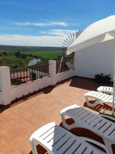 阿尔莫多瓦尔德尔里奥Lonja del Ribacillo, Casa Rural的阳台配有白色椅子和遮阳伞。