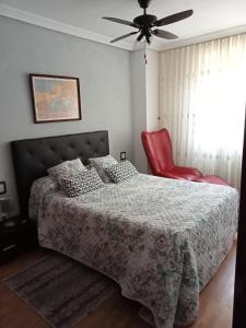 巴利亚多利德Confortable y luminoso apartamento的一间卧室配有一张床和一张红色椅子