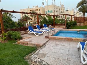 赫尔格达Serafy City Center Hostel and Pool for Foreigners Adults Only的一组蓝色的躺椅,位于游泳池旁
