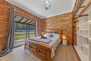 WilliamtownThe Weltara - 6 bedrooms House Near Anna Bay的砖墙卧室设有一张床和一个大窗户