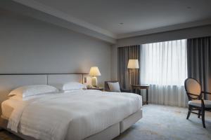 高雄汉来大饭店的酒店客房带大型白色床和椅子