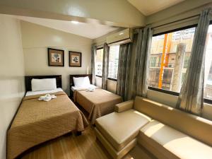 马尼拉马尼拉石楼酒店的客房设有两张床、一张沙发和一个窗口。