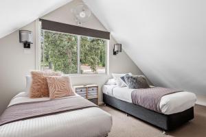 康约拉The Leaning Oak Holiday Lifestyles - Lake Conjola的阁楼卧室设有两张床和窗户。