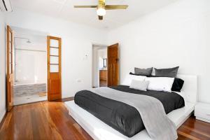 雷德克利夫2-bedroom Cottage in Redcliffe - 6A的白色卧室配有黑色的床和吊扇