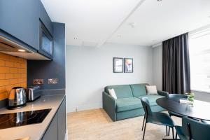 伦敦Staycity Aparthotels London Greenwich High Road的厨房以及带沙发和桌子的客厅。