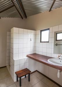 纳穆托尼Onguma Tamboti Campsite的一间带水槽和木凳的浴室