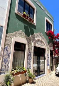 波尔蒂芒Charming Portuguese style apartment, for rent "Vida à Portuguesa", "Amêndoa or Limão" Alojamento Local的绿色建筑,上面有窗户和盆栽植物