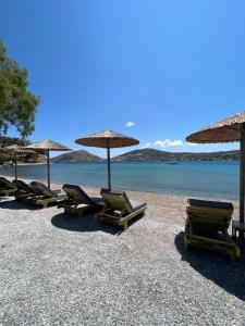 阿林达Alidian bay Suites Leros的海滩上的一组躺椅和遮阳伞