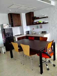 考陶Las Tortugas, Cozy condominium on Khao Tao beach, Hua Hin的厨房配有黑色桌椅和冰箱。