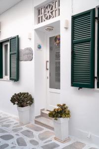 提诺斯阿格里科拉汽车旅馆的白色的房子,有绿色百叶窗和两株盆栽植物