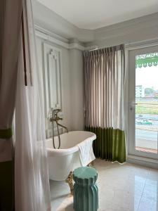 清迈Wiang Ville Boutique Hotel的带浴缸的浴室和大窗户