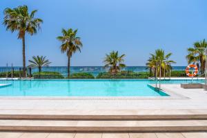 马贝拉El Fuerte Marbella的一座棕榈树和海洋游泳池